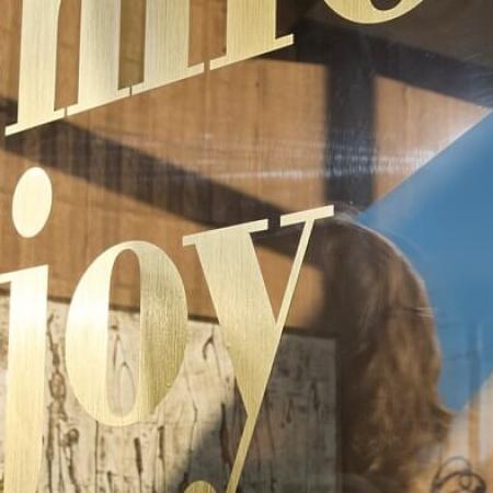 Woman removing application tape from a VinylEfx gold vinyl window graphic