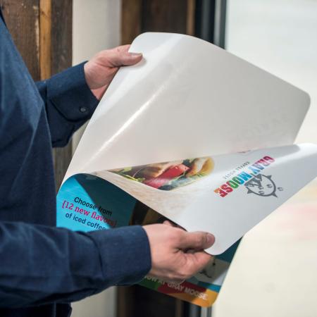 person removing the application film from a Sign-Ad with a clear barrier film